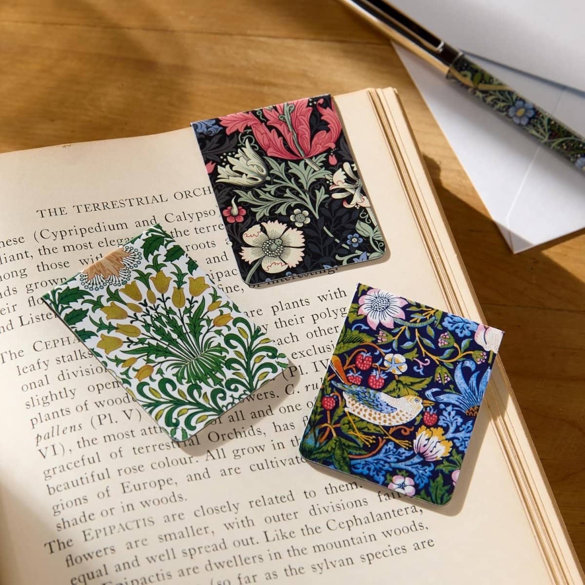 Magnetic bookmarks - William Morris från Galison. Tre bokmärken med William Morris motiv, en sitter insatt i en läsebok och de andra två ligger bredvid. - Tidformera