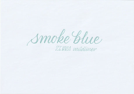 Handskriven text med orden "smoke blue" och "ZEBRA mildliner" i blå färg, skriven med Zebra Mildliner Brush Pen i färgen Smoke Blue.