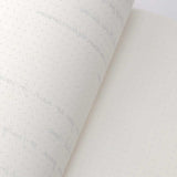 TomoeRiver Notebook softcover - A5 - Dot Grid från Sakae TP. En uppslagen skrivbok med en inlaga med prickar. Baksidan av ett ark och skrift skymtar genom från andra sidan. 